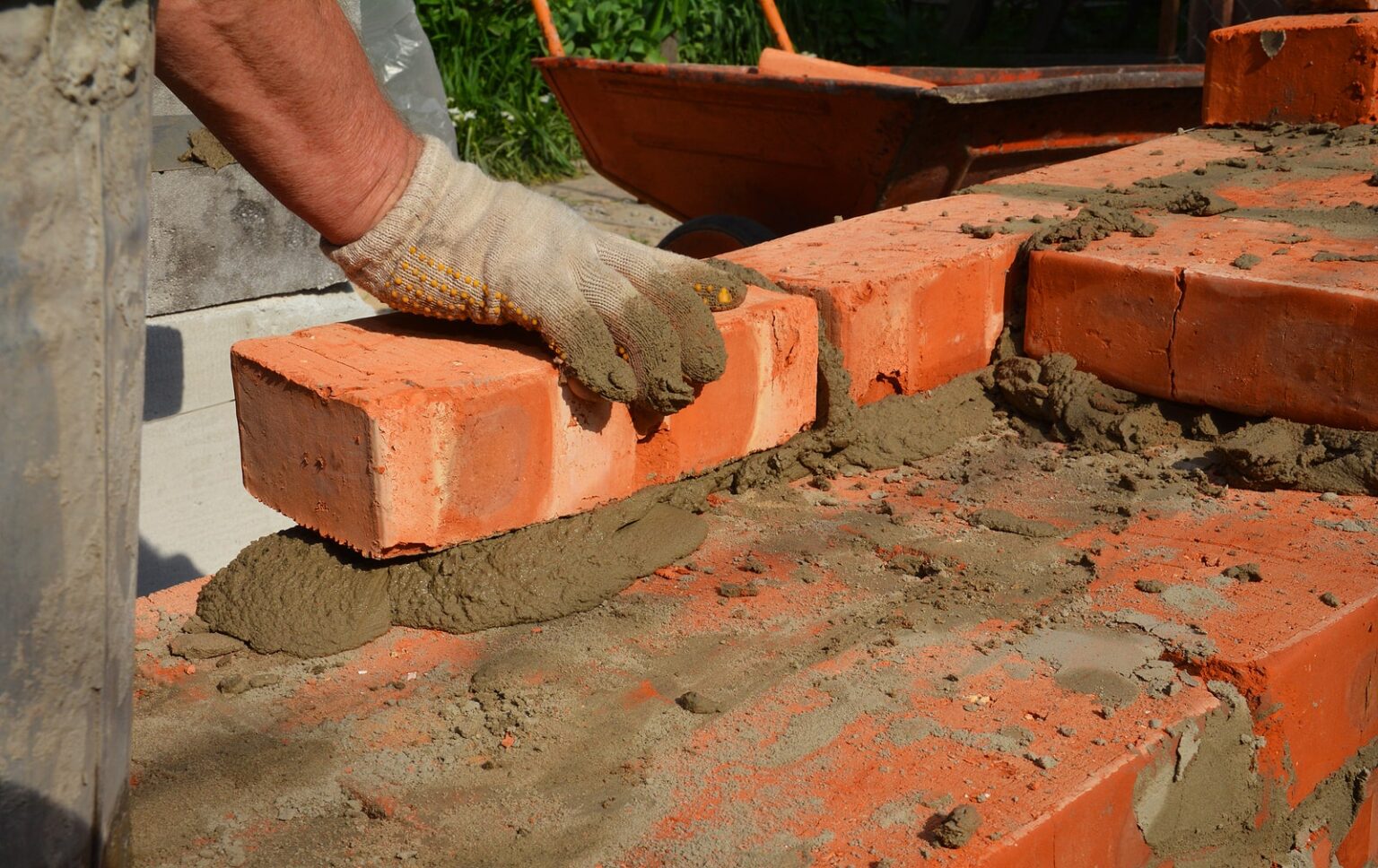 A person laying bricks into a foundation of a home.