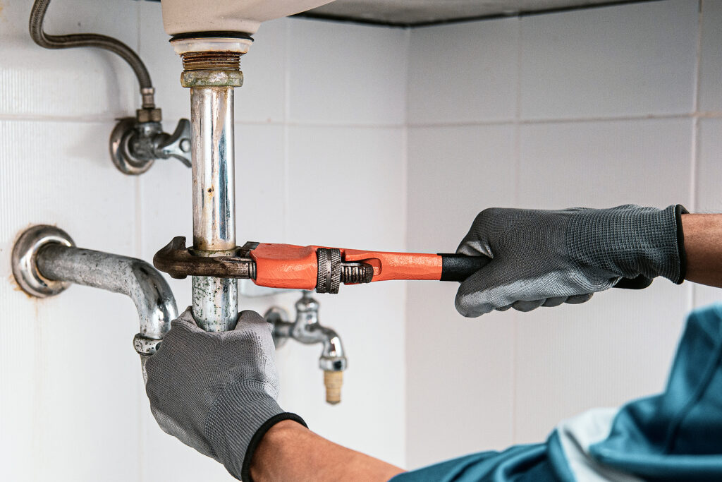 Image of a water leak technician repairing a pipe on VCE's website